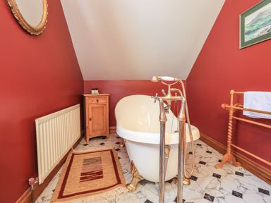 A bathroom with a white clawfoot bathtub and red walls at The Stables in Ambleside