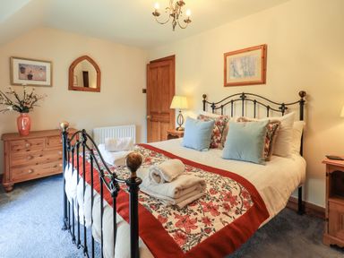 A bedroom with a black metal bed frame and floral bed runner at The Stables in Ambleside