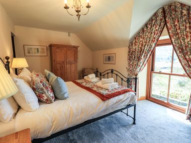 A bedroom with a bed towels on top and floral curtains by a window at The Stables in Ambleside