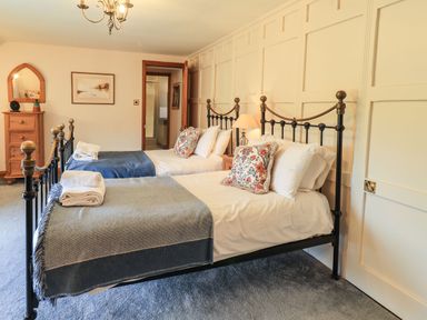 A bedroom with two single beds bedside table chest of drawers and a mirror at The Stables in Ambleside
