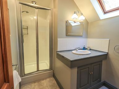 A bathroom with a shower enclosure a sink with countertop mirror and skylight at The Stables in Ambleside