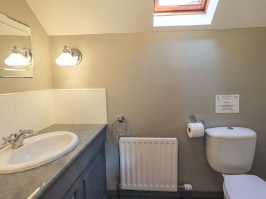 A bathroom with a sink countertop cabinet a radiator and a toilet at The Stables in Ambleside