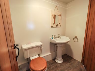 A small bathroom with a toilet and pedestal sink with a mirror above at The Stables in Ambleside