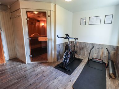 A room with an exercise bike, workout bench, foam roller, and a sauna at The Stables in Ambleside