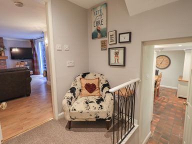A hallway with a chair and wall art at Chapel Hill Cottage in Ambleside