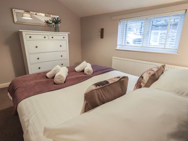 A bedroom with a bed and dresser at Chapel Hill Cottage, Ambleside
