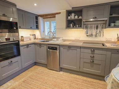 A kitchen with grey cabinets appliances hanging utensils and a window at Hannakin Barn Hawkshead
