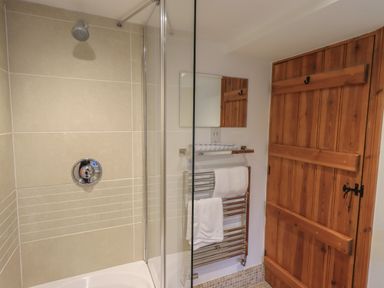 A bathroom with a shower area glass panel towel rack with towels wooden door at Hannakin Barn in Hawkshead