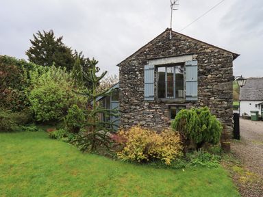 Exterior of a stone house with blue shutters and garden plants at Hannakin Barn in Hawkshead