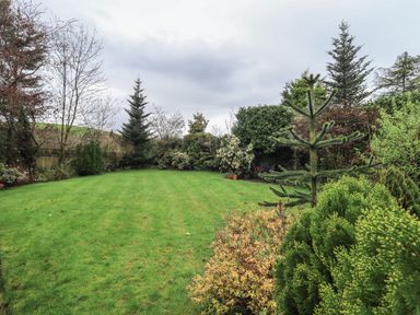 A garden with grass and various trees and bushes at Hannakin Barn in Hawkshead