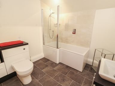 A bathroom with a bathtub, shower, toilet and sink at South View in Keswick
