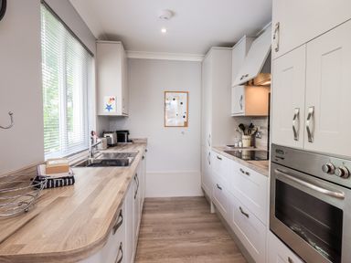 A kitchen with wooden countertops white cabinets a built in oven and a window with blinds at Fairview in Bowness