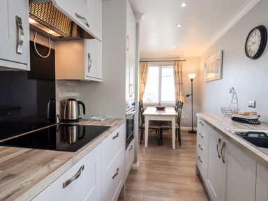 A kitchen with a stovetop kettle dining table and chairs near a window at Fairview in Bowness