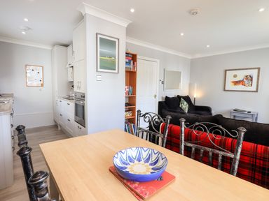 A kitchen and living area with a wooden dining table and metal chairs at Fairview in Bowness