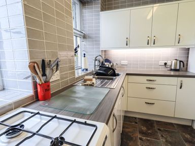 A kitchen with a gas stove countertop utensils sink and kettle at Gildabrook Cottage in Bowness