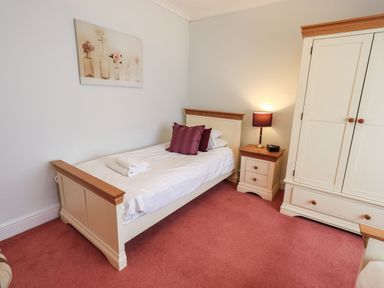 A bedroom with a single bed nightstand with a lamp and a wardrobe at Gildabrook Cottage in Bowness