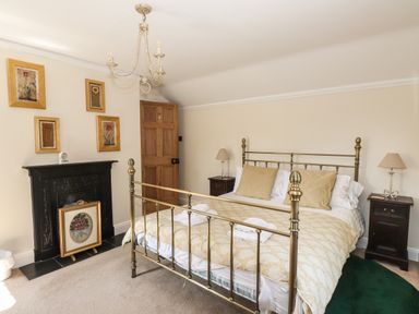 A bedroom with a brass bed frame bedside tables lamps and framed pictures on the wall at Hodge How Cottage in Windermere