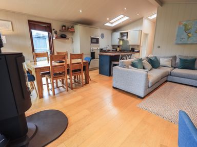 A living room with a grey sectional sofa and kitchen with wooden dining table and chairs at Beck of Beyond in Ambleside