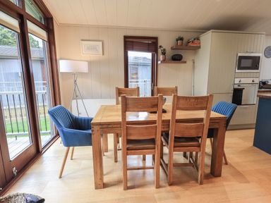 A dining area with a wooden table and chairs next to large windows at Beck of Beyond in Ambleside