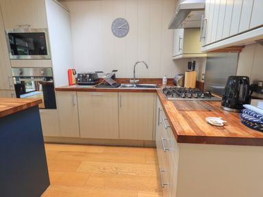 A kitchen with wooden countertops a gas stove a microwave toaster and a kettle at Beck of Beyond in Ambleside