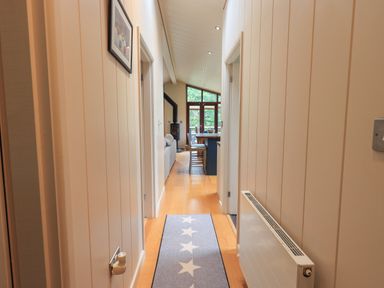 A narrow hallway with a carpet runner and doors on each side leading to a living area and kitchen at Beck of Beyond in Ambleside