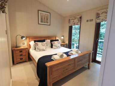 A bedroom with a wooden bed and bedside tables with lamps and floral cushions at Beck of Beyond Ambleside