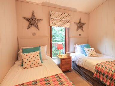 A bedroom with two single beds a wooden nightstand and a window with polka dot blinds at Beck of Beyond in Ambleside