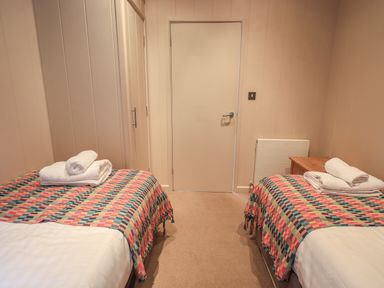 A bedroom with two single beds with colorful blankets and folded towels on each bed at Beck of Beyond in Ambleside