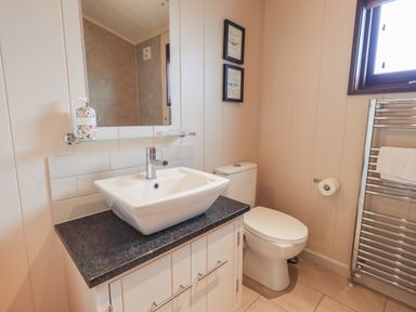 A bathroom with a white sink on a black countertop a toilet next to a window and a towel radiator at Beck of Beyond in Ambleside