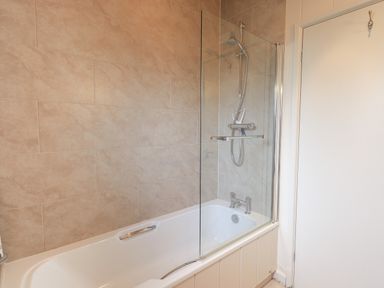 A bathroom with a bathtub shower combination and tiled walls at Beck of Beyond in Ambleside