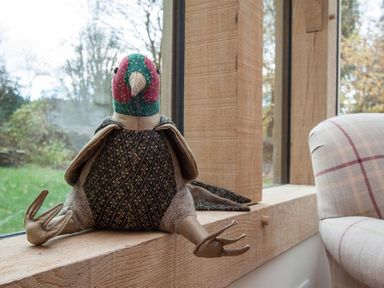A fabric bird decoration on a wooden windowsill next to a checked armchair at Old Droomer in Windermere
