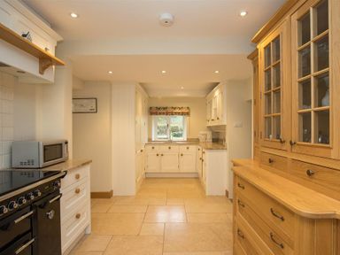 A kitchen with white cabinets a black stove a microwave and a wooden cupboard at Old Droomer in Windermere