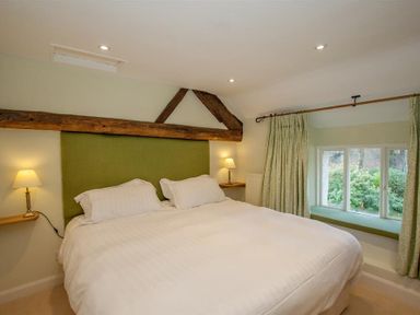 A bedroom with a large bed two lamps and a window seat at Old Droomer in Windermere