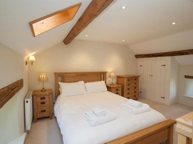 A bedroom with a wooden bed white bedding bedside tables lamps dresser and a skylight at Old Droomer in Windermere