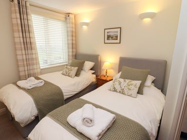 A bedroom with two single beds bedside table and window at Kirkstones in Keswick