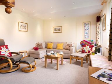 A living room with a beige sofa yellow and patterned cushions a wooden coffee table and armchairs at Lingmoor View in Chapel Stile