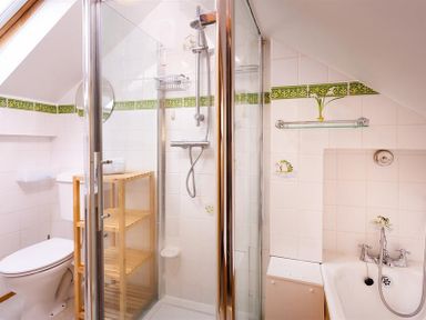 A bathroom with a toilet shower with glass doors wooden shelving and a bathtub with a faucet at Lingmoor View in Chapel Stile