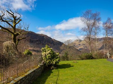 A garden with grass bushes and leafless trees with mountains in the background at Lingmoor View in Chapel Stile