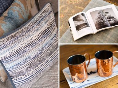 Close up of cushions an open book with black and white photos and two copper mugs on a tray at High Cunsey Farm Far Sawrey