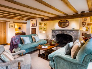 A living room with exposed wooden beams stone fireplace sofas and armchairs at High Cunsey Farm in Far Sawrey