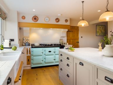 A kitchen with a blue stove white countertops wooden cabinets and hanging lights at High Cunsey Farm in Far Sawrey