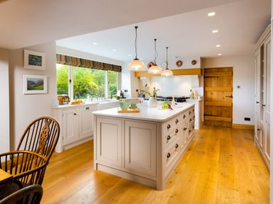 A kitchen with a large island countertop and wooden chairs at High Cunsey Farm in Far Sawrey