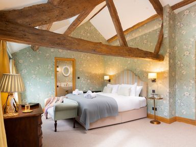 A bedroom with exposed wooden beams a bed with pillows and blankets bedside tables and a lamp at High Cunsey Farm in Far Sawrey