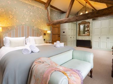 A bedroom with a large bed including rolled towels a couch a wooden door wardrobes and exposed wooden beams at High Cunsey Farm in Far Sawrey