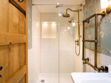 A bathroom shower area with brass fixtures and tiled walls at High Cunsey Farm in Far Sawrey