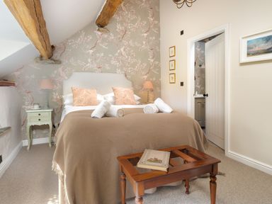 A bedroom with a bed covered in beige blankets and rolled towels at High Cunsey Farm in Far Sawrey