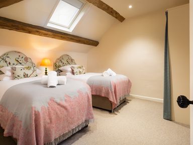 A bedroom with two single beds with patterned headboards and blankets under a skylight at High Cunsey Farm in Far Sawrey