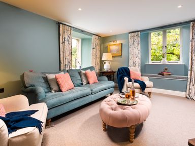 A living room with blue and white armchairs a blue sofa and a pink ottoman at High Cunsey Farm in Far Sawrey