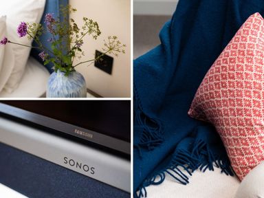 A vase with flowers on a bedside table a sonos speaker a blue blanket and a red patterned cushion at High Cunsey Farm in Far Sawrey