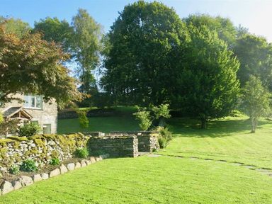 A garden with stone walls green grass and trees at High Cunsey Farm in Far Sawrey